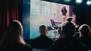 Presenter in front of a video wall.