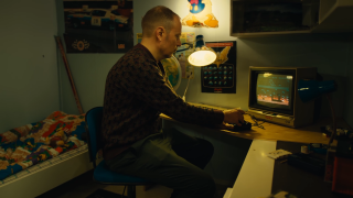 A picture of a man playing video games in a 1980’s setting.