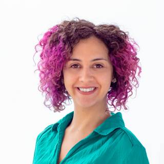 A smiling woman with colourful and curly hair.
