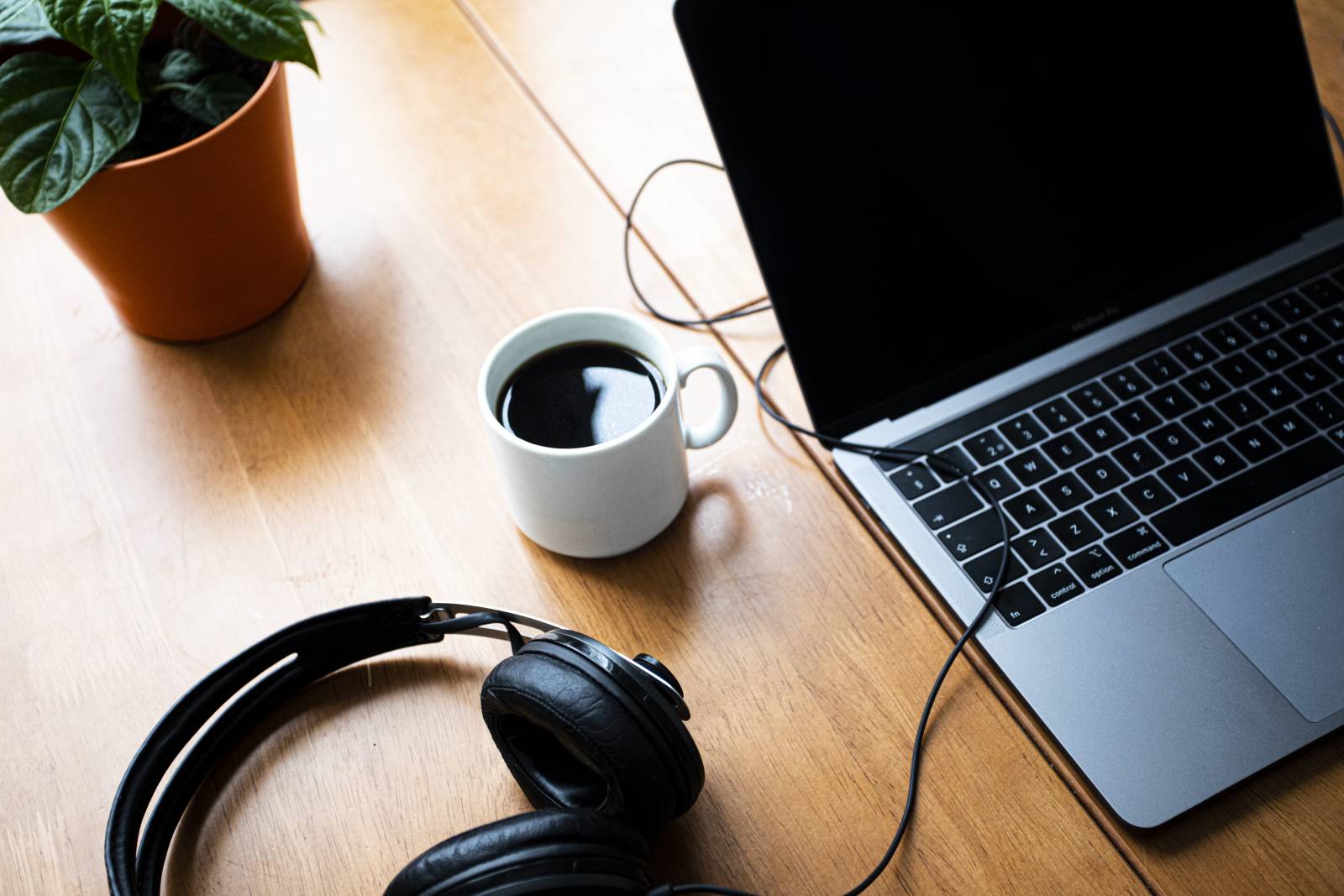 A cup of coffee, laptop and headphones