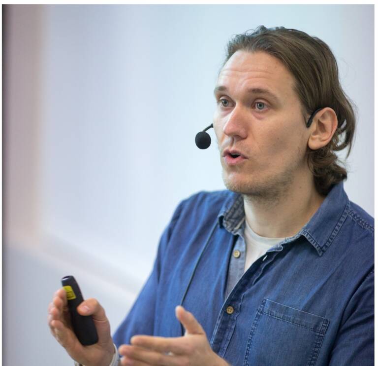 Ass. Prof. Tero-Petri Ruoko talking with both hands lifted in a gesture at a LIBER event