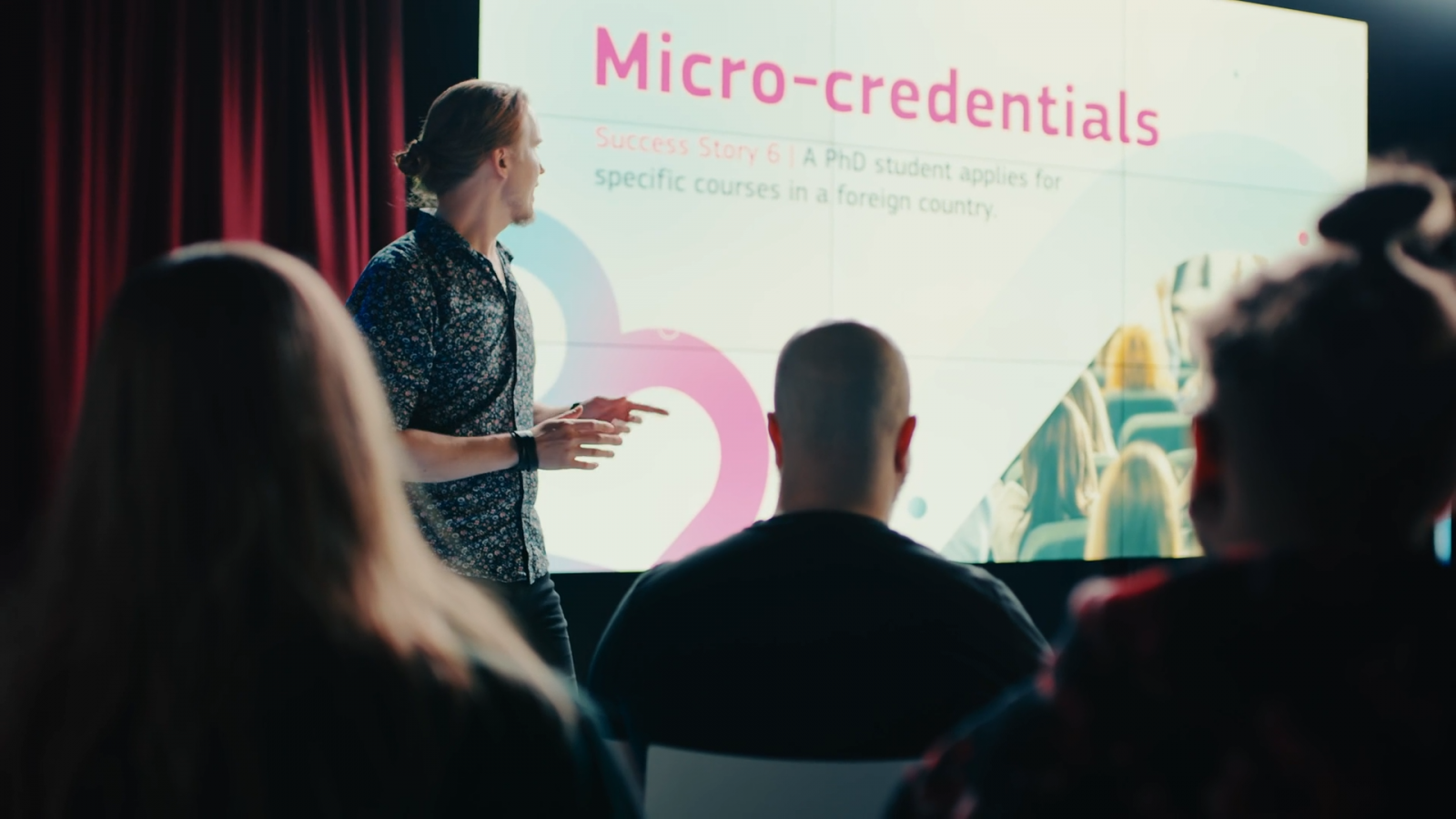 A man teaching in front of video wall