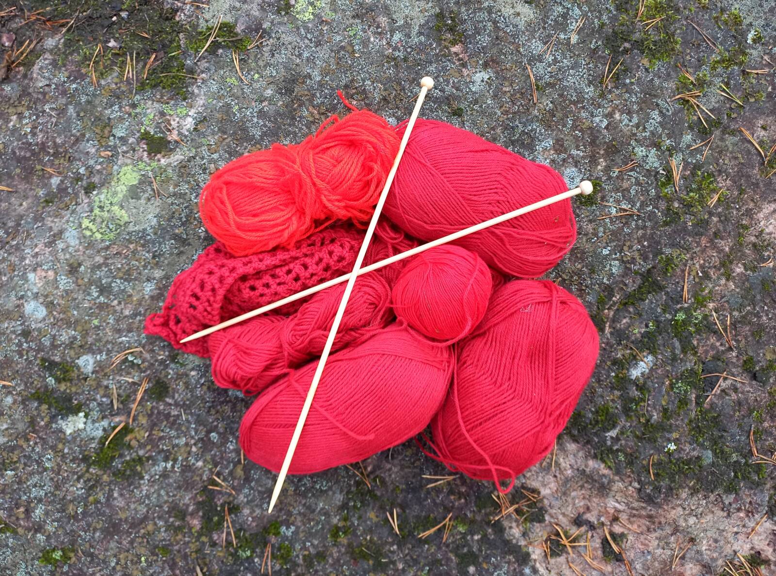 Knitting needles and red yarn.