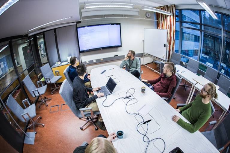Wideangle photo from above meeting room desk showing staff around the table