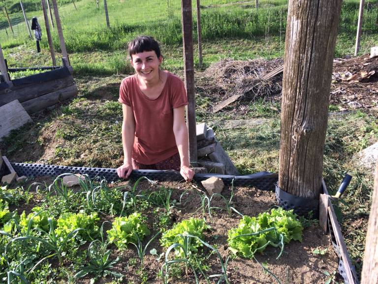 Smiling woman next to the flowerbed.