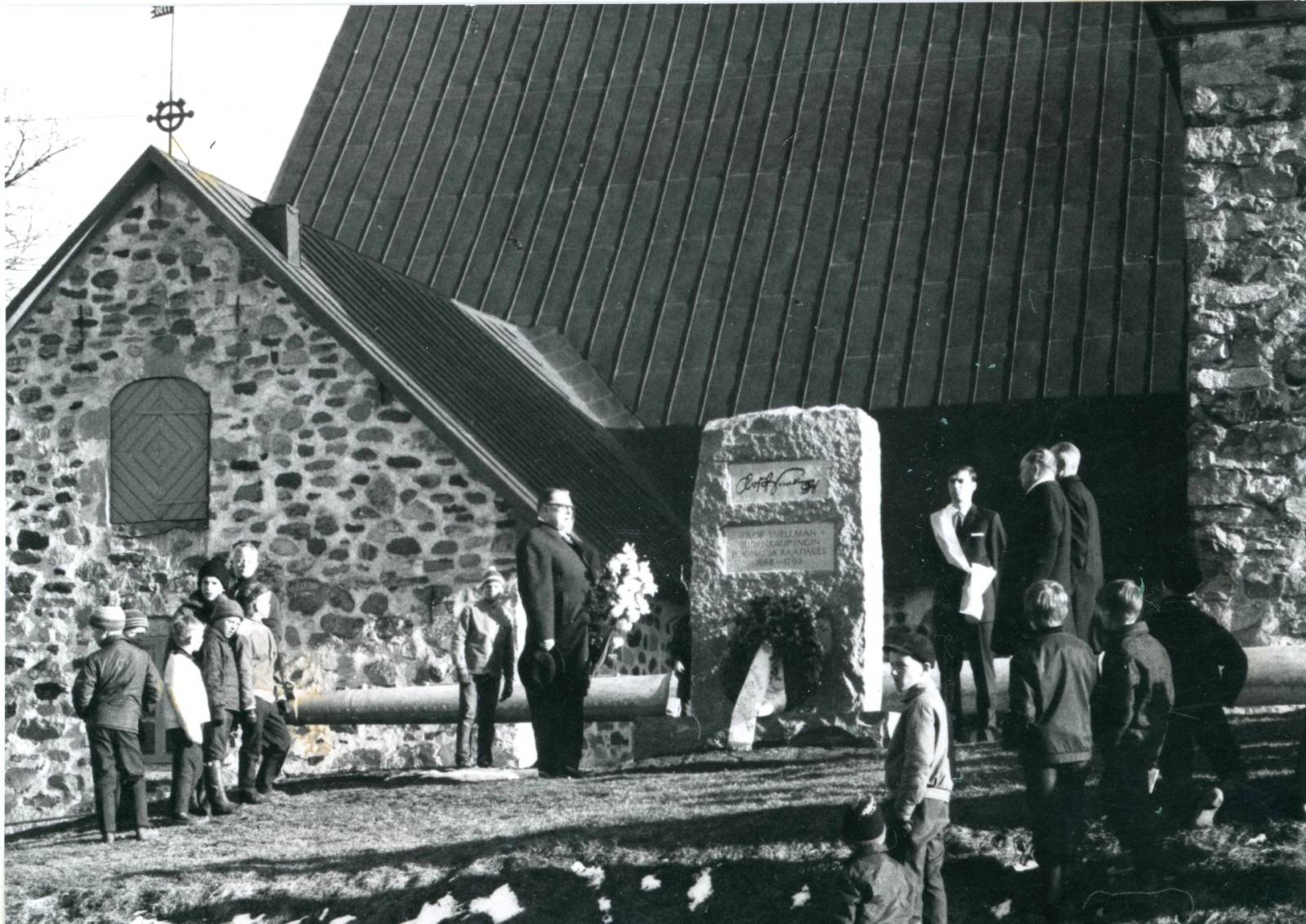 Mustavalkoinen valokuva, jossa taustalla Uudenkaupungin kirkko ja etuosassa muistomerkki.