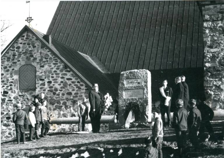 Mustavalkoinen valokuva, jossa taustalla Uudenkaupungin kirkko ja etuosassa muistomerkki.