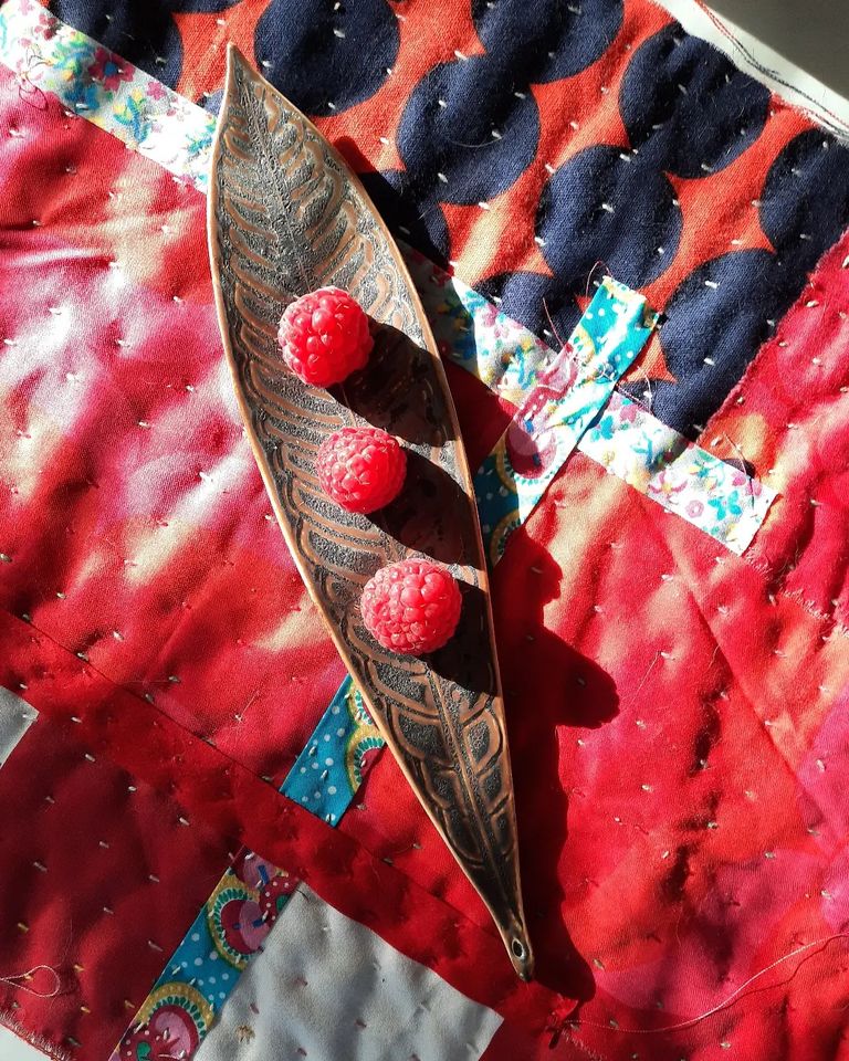 Kuvassa astia ja kolme vadelmaa.