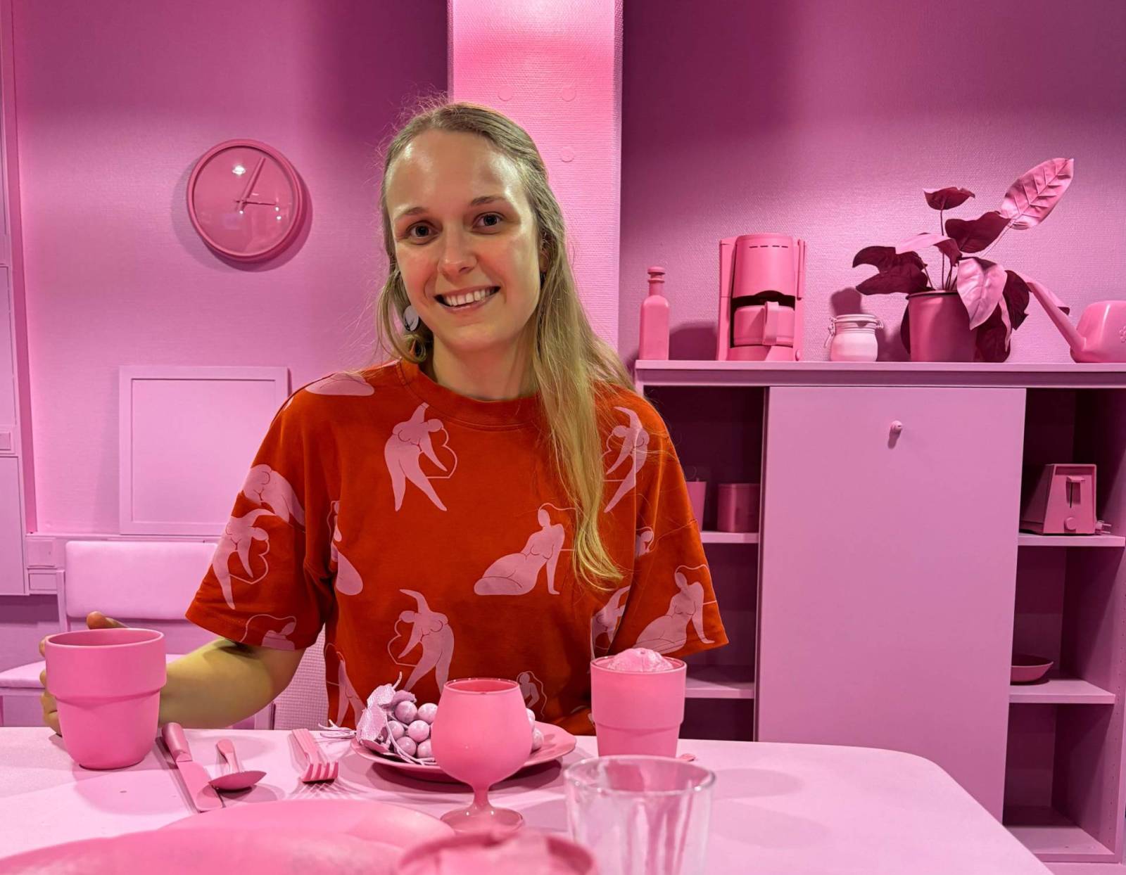 Vaalenanpunainen huone, jossa istuu nainen pöydän ääressä.