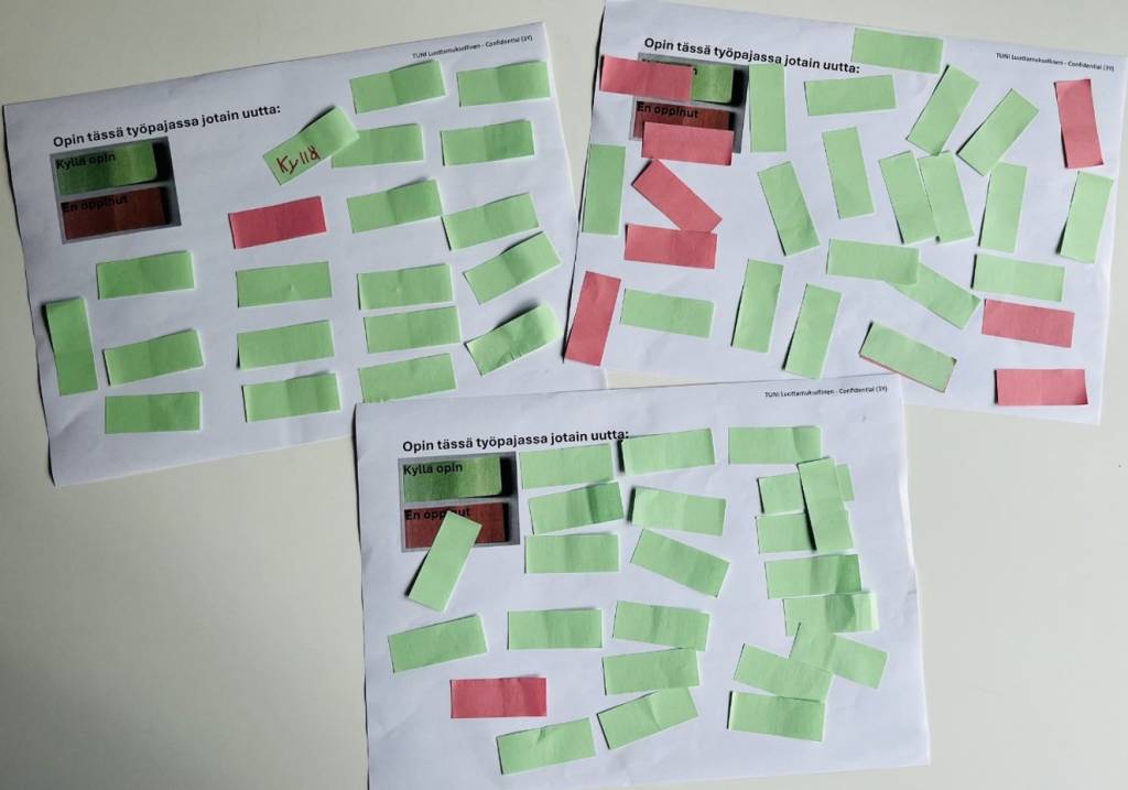 Three sheets of paper on which green and red post-it notes have been placed.
