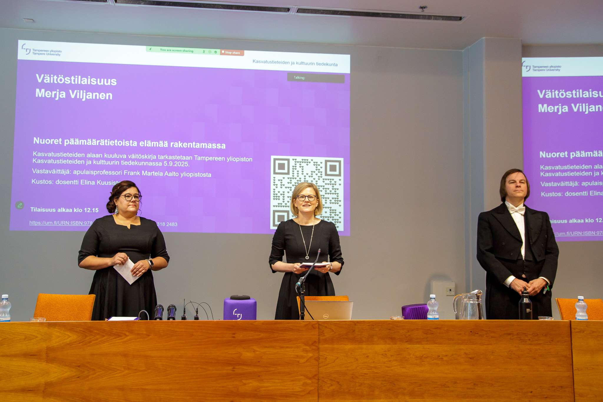 Väitöstilaisuuden alussa edessä seisovat Merja Viljanen, Elina Kuusisto ja Frank Martela.