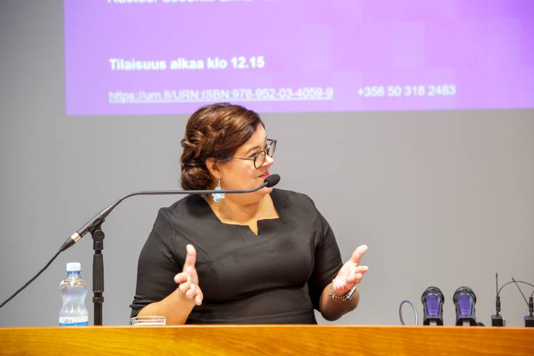 Merja Viljanen väitöstilaisuudessan luentosalin etuosassa.