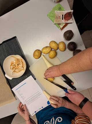 Lähikuva käsistä, jotka pilkkovat juureksia