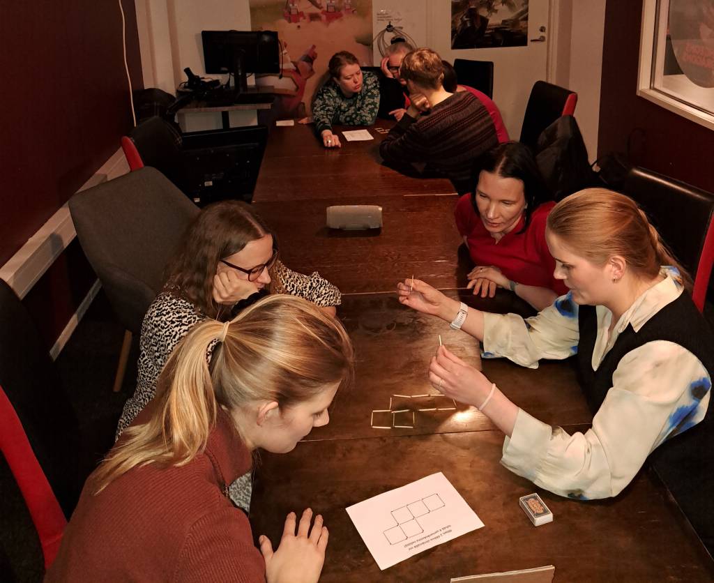 People sitting on a long table solving a puzzle