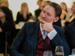 Dr. Tero-Petri Ruoko in a suit, sitting at the table and looking to the left with his chin supported by his hand.
