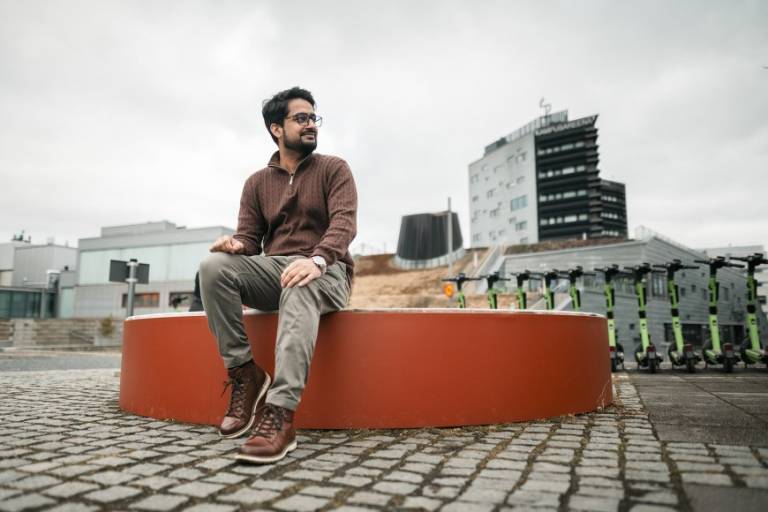 Abrar Akram sitting on a bench outside Tampere University Hervanta campus.