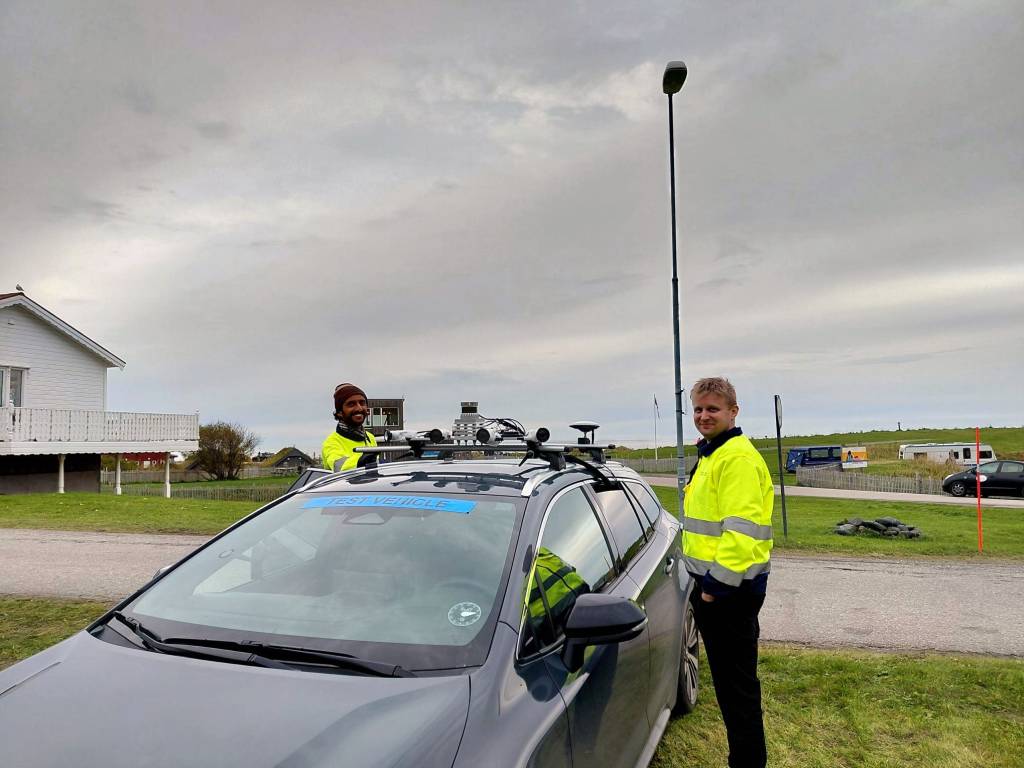 Two people standing next to a test vehicle.