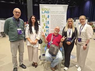 Five EDU-LAB researchers posing in front of the poster