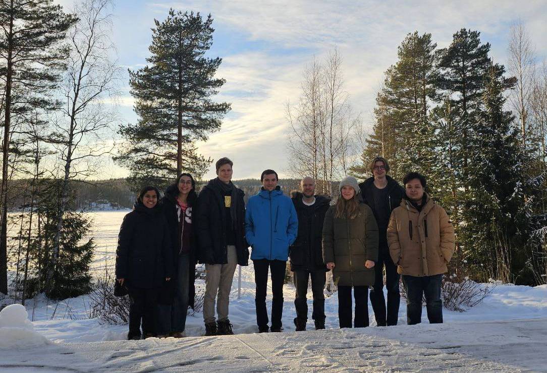 The research group standing together outdoors in a snowy, forested landscape during the 2026 retreat.