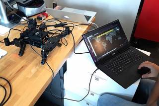 Drone on a table connected to a laptop with world map view.