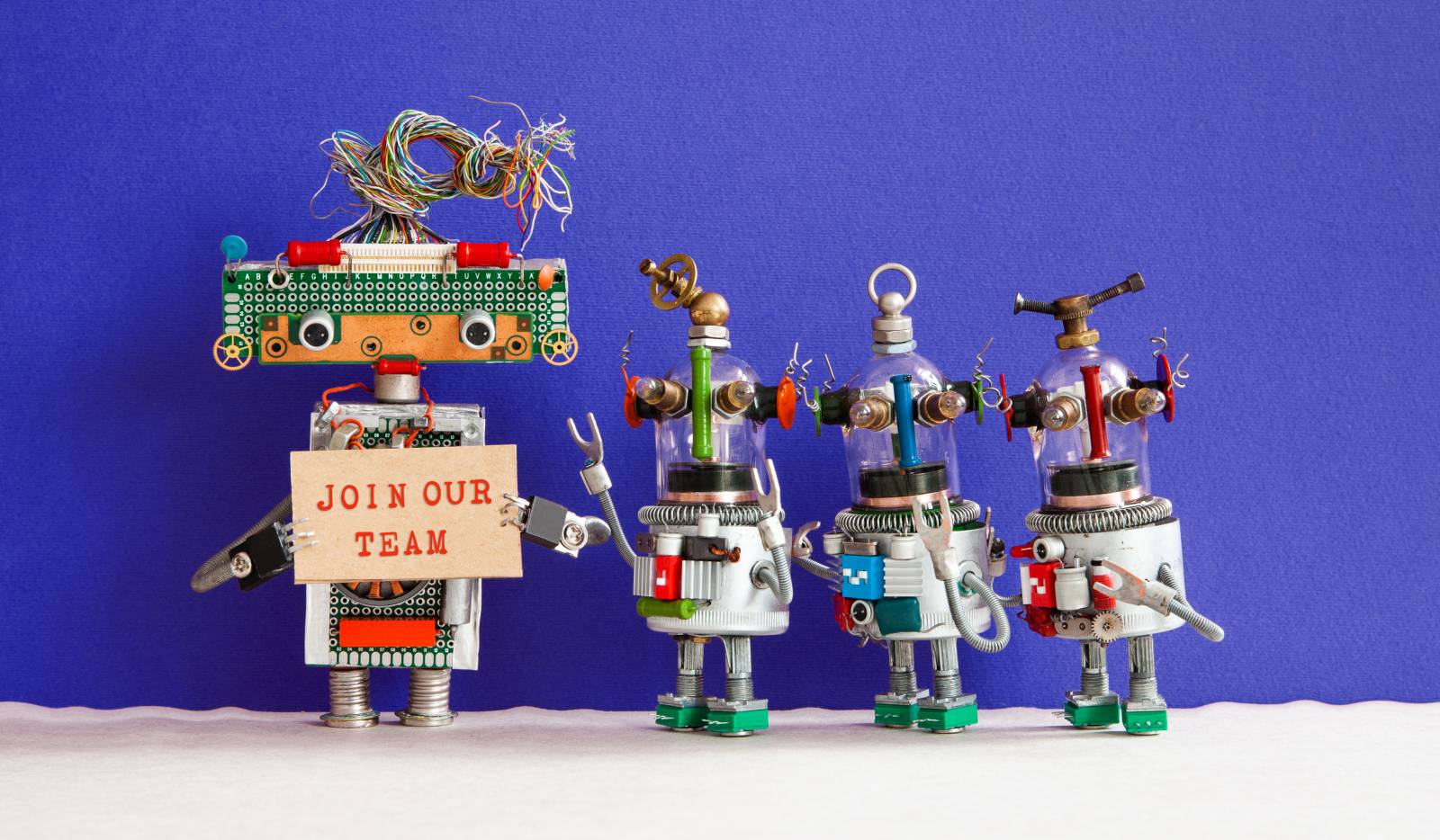 picture of funny robots holding a sign "join our team"