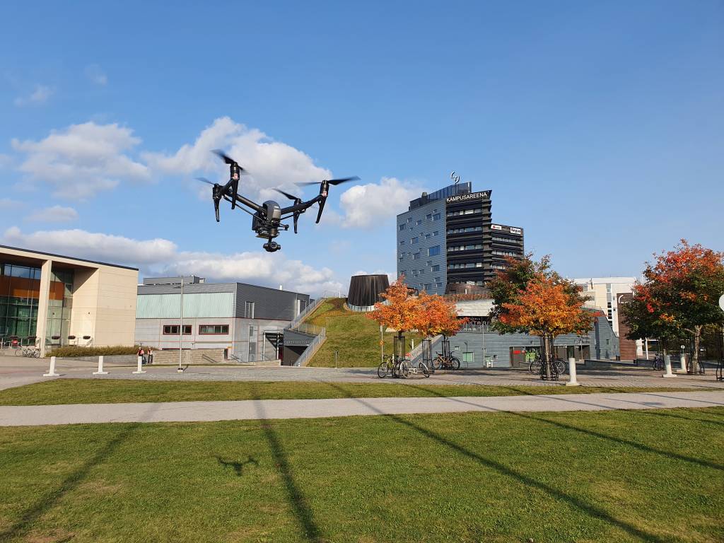 Picture taken from the front yard of Hervanta campus showing drone in the air and Kampusareena in the background.