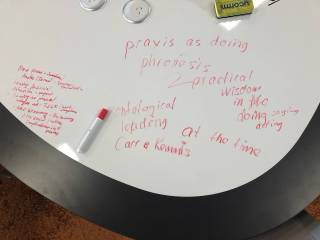 Research planning, text "praxis as doing" and other notes written on the table surface.