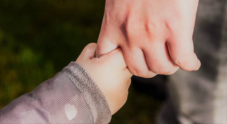 Photo of a child holding an adult's hand