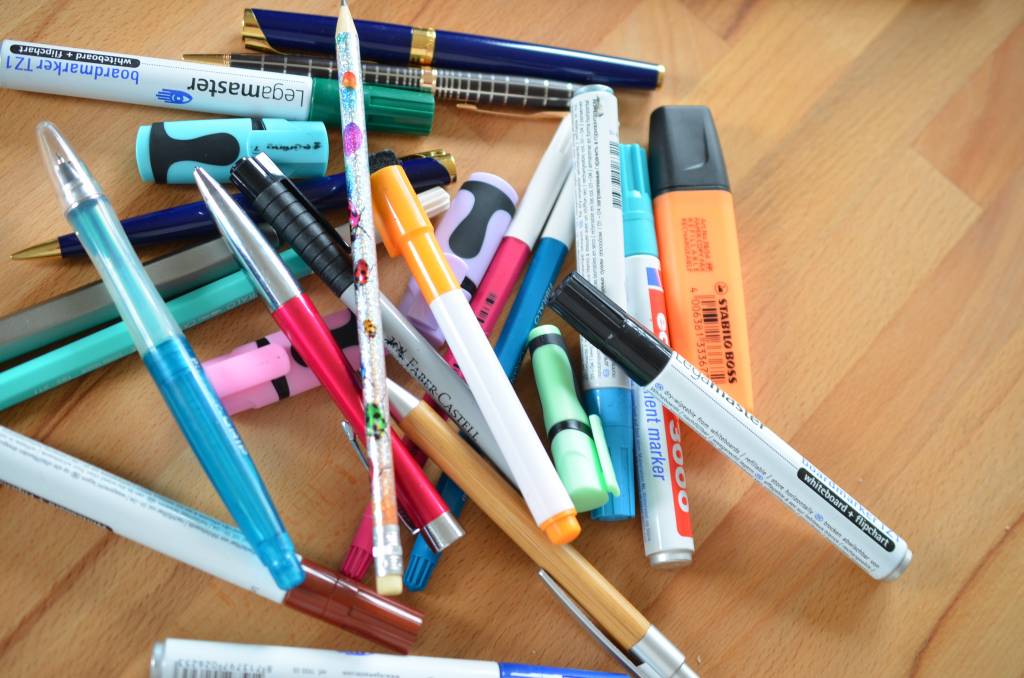Pile of colorful pens on a wooden surface