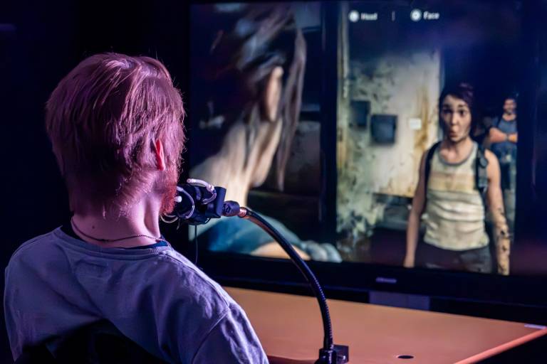Takaa otettu kuva miehestä pelaamassa The Last of Us 2 peliä suuohjaimella.