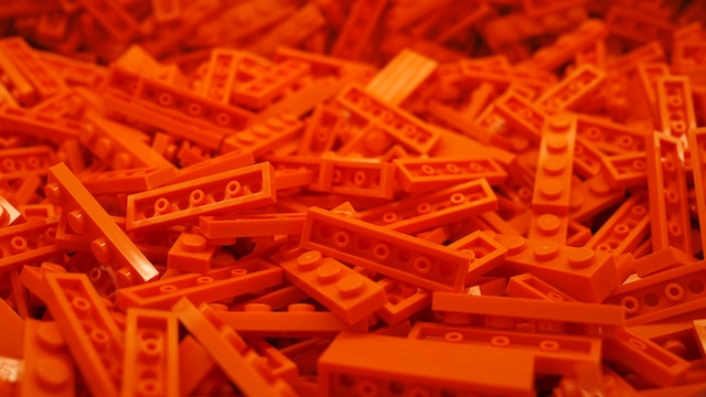 A sprawl of bright orange puzzle bricks, similar to Lego, covering a table.