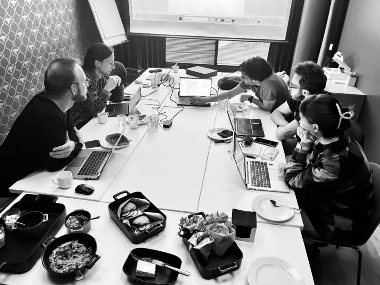 Five researchers working together on laptops around a table.