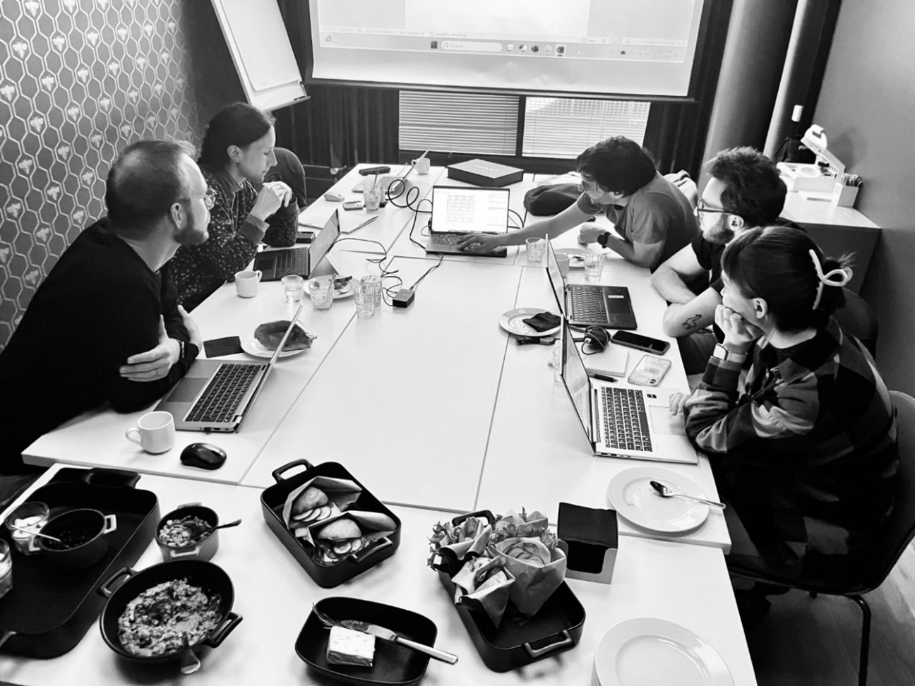 Five researchers working together on laptops around a table.