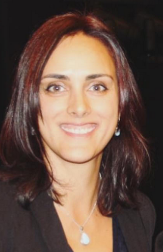 A woman with long, mahogany brown hair and brown eyes smiles at the camera.