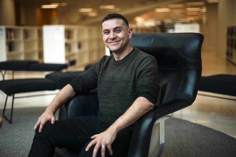 Mikko Meriläinen is sitting in an armchair in the library