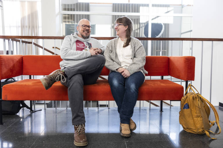 Tutkijat Mikko Hautakangas ja Matleena Ylikoski juttelevat oranssilla sohvalla istuen.